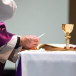 a priest is writing on a paper at a table