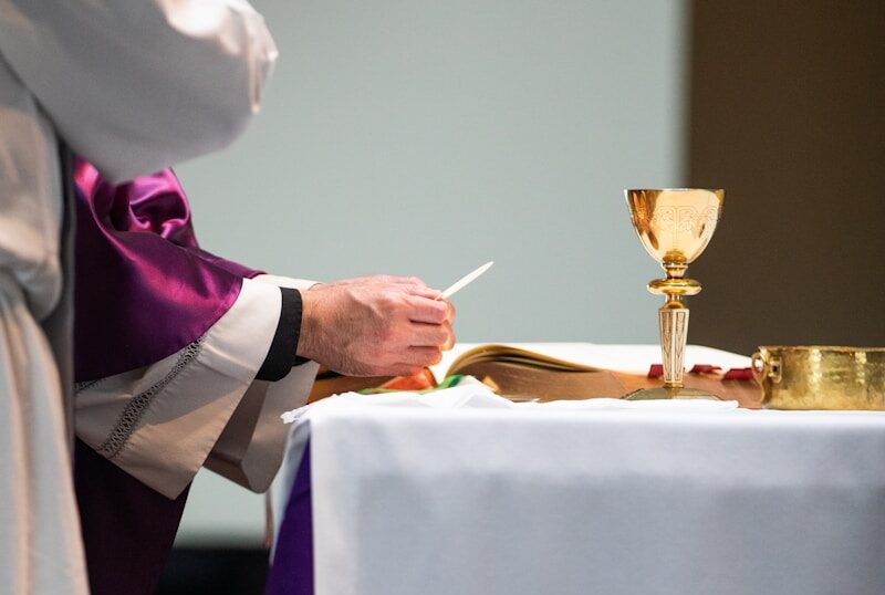 a priest is writing on a paper at a table